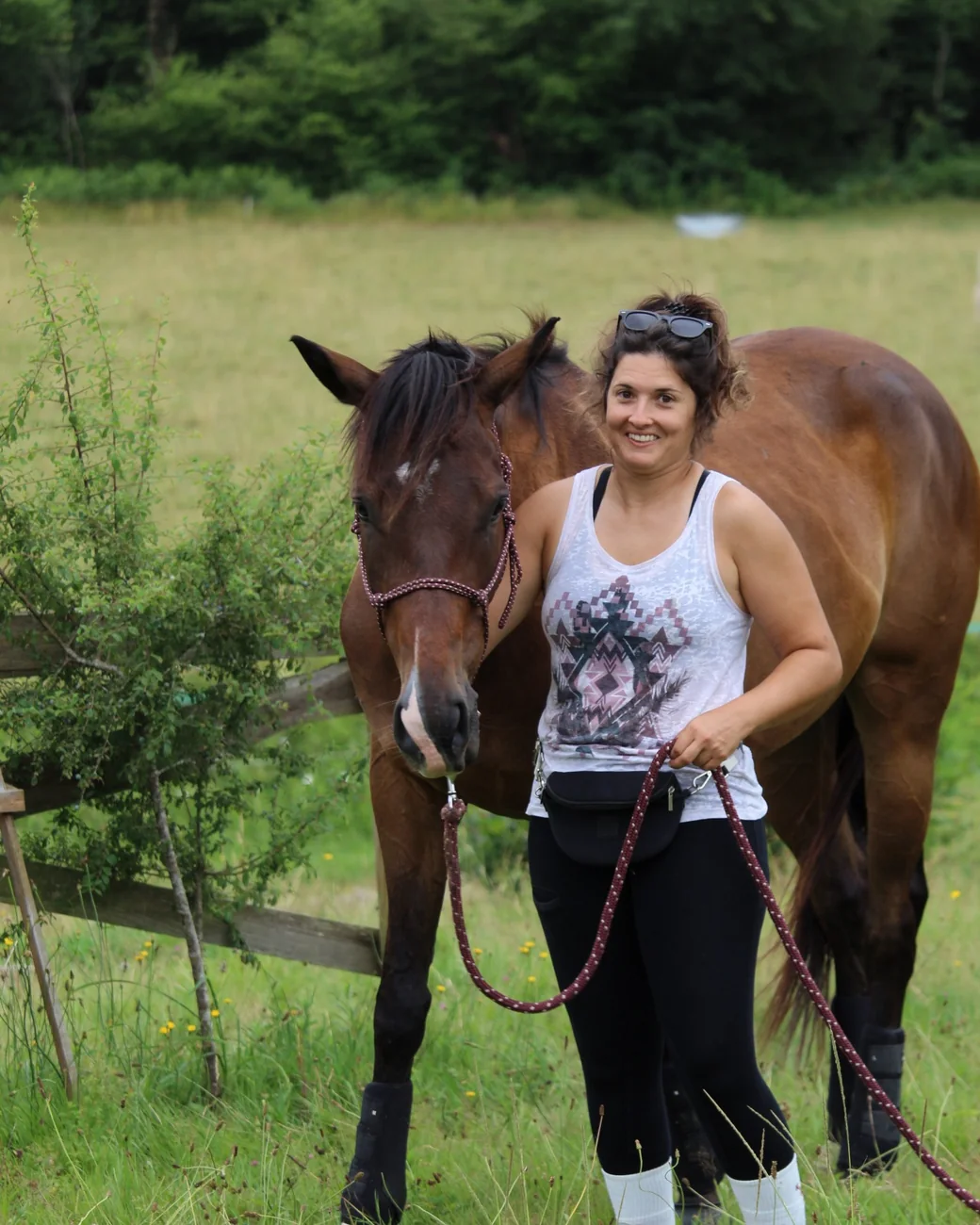 Pauline marche aux côtés de son cheval tenu en licol, le sourire aux lèvres
